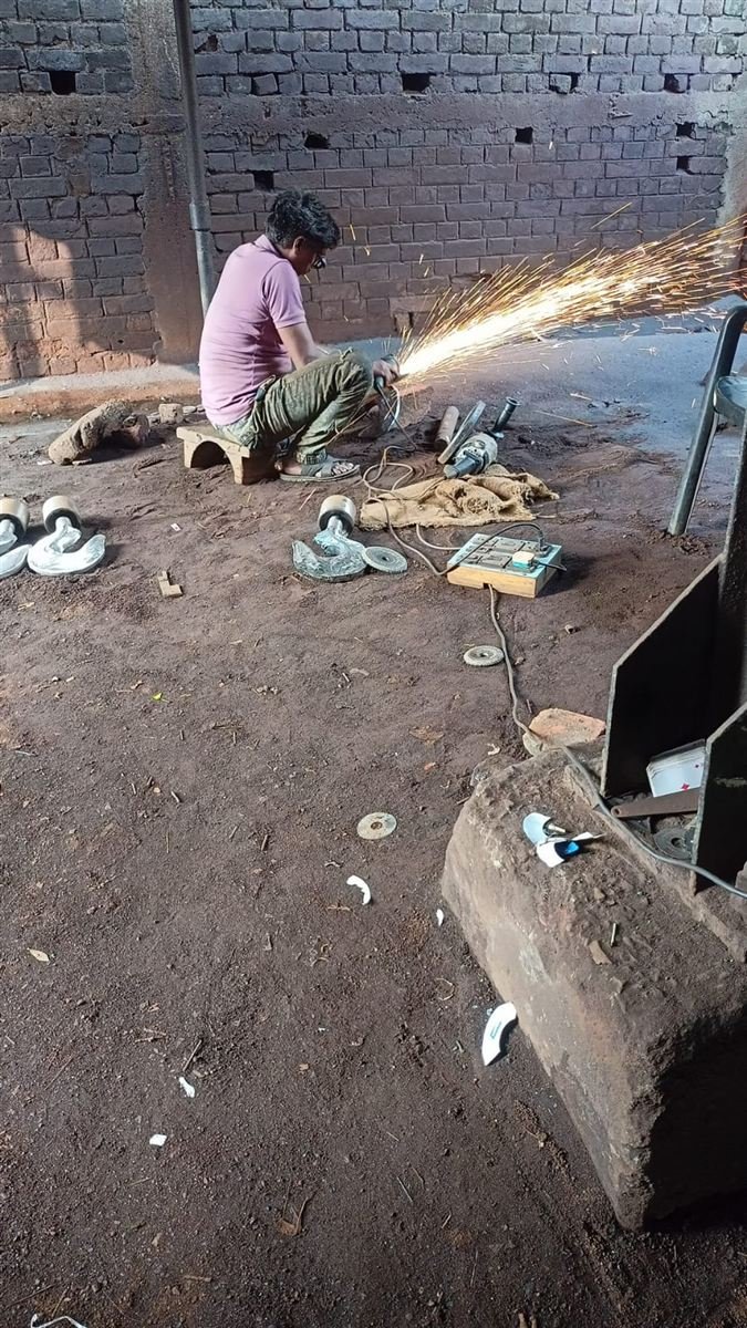 Craftsman grinding a crane hook in the Indian Fabricators workshop, sparks flying